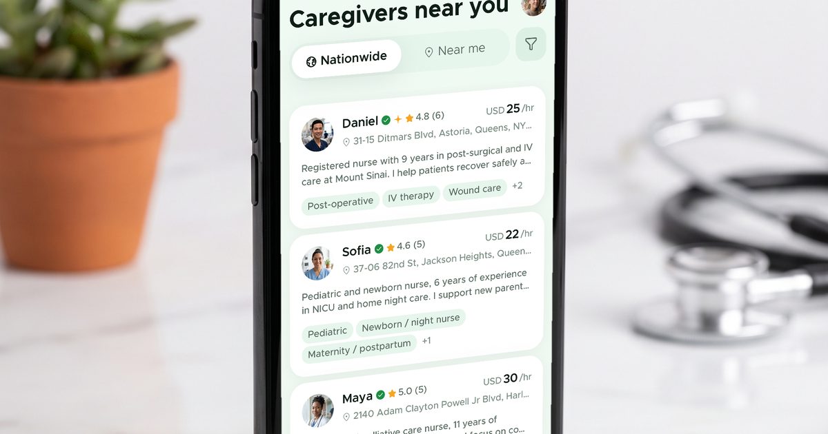 Un teléfono sobre un escritorio con la lista «Cuidadores cerca de ti» de SoftCare, con distintivos de verificación y tarifas por hora