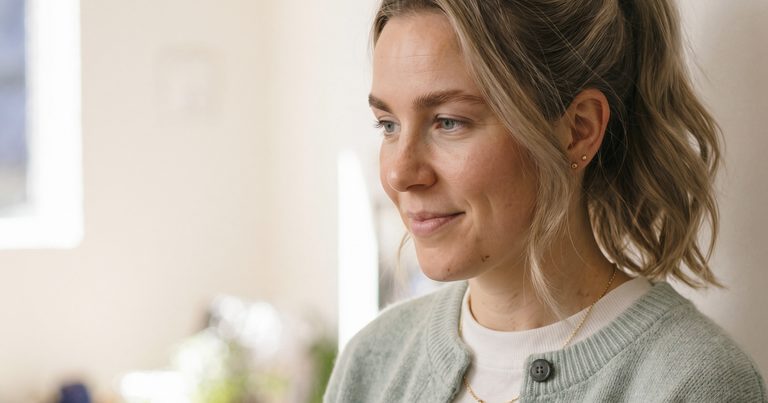 A woman standing in her kitchen, thinking over care options for a parent
